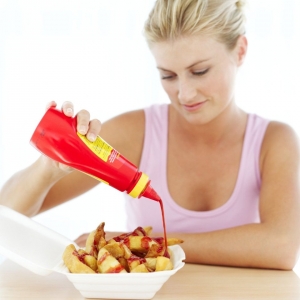 Getty -Woman pouring tomato ketchup on a box of potato wedges